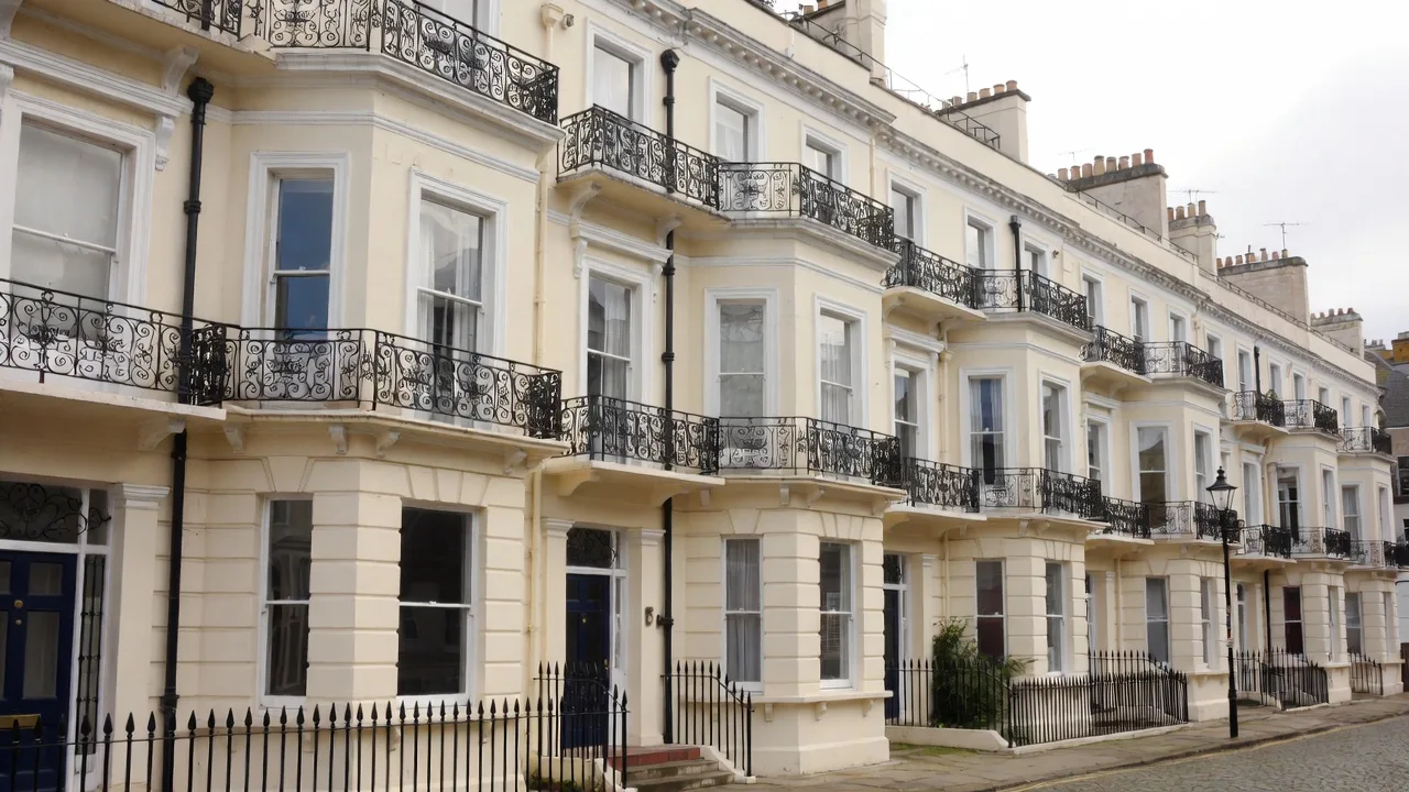 A Regency terrace of cream stucco townhouses with cast-iron balconies and tall sash windows