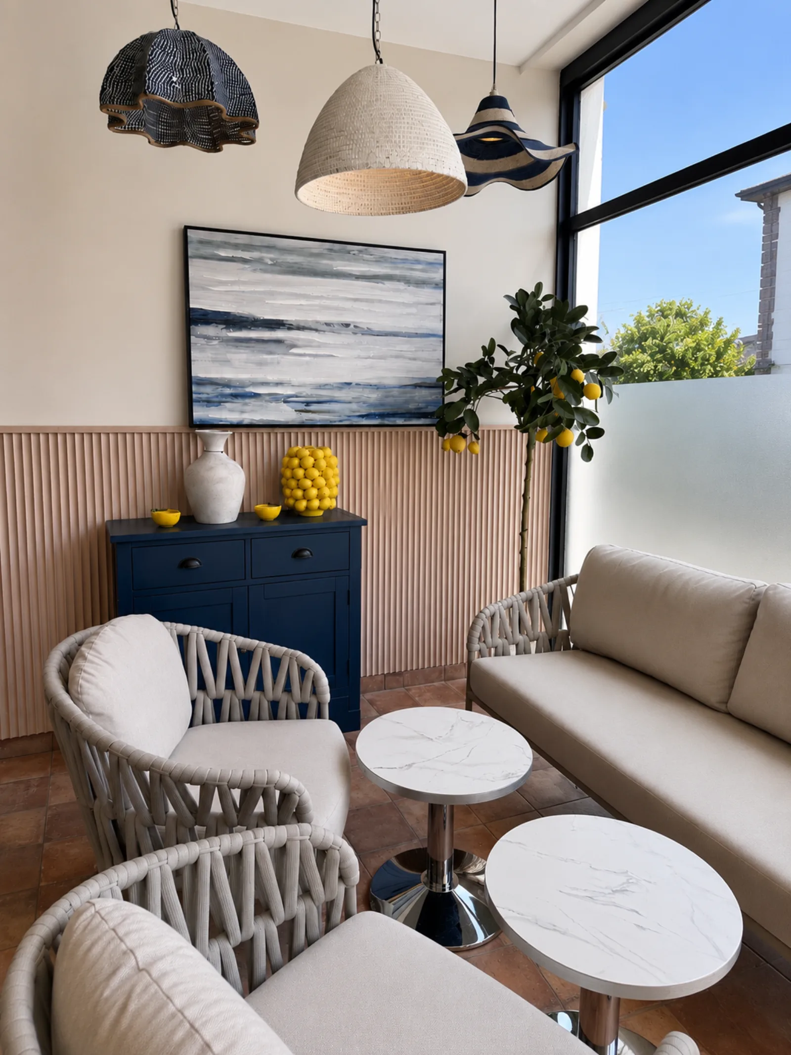 The chill out zone, with rope backed armchairs, a linen sofa, marble tables and a navy dresser