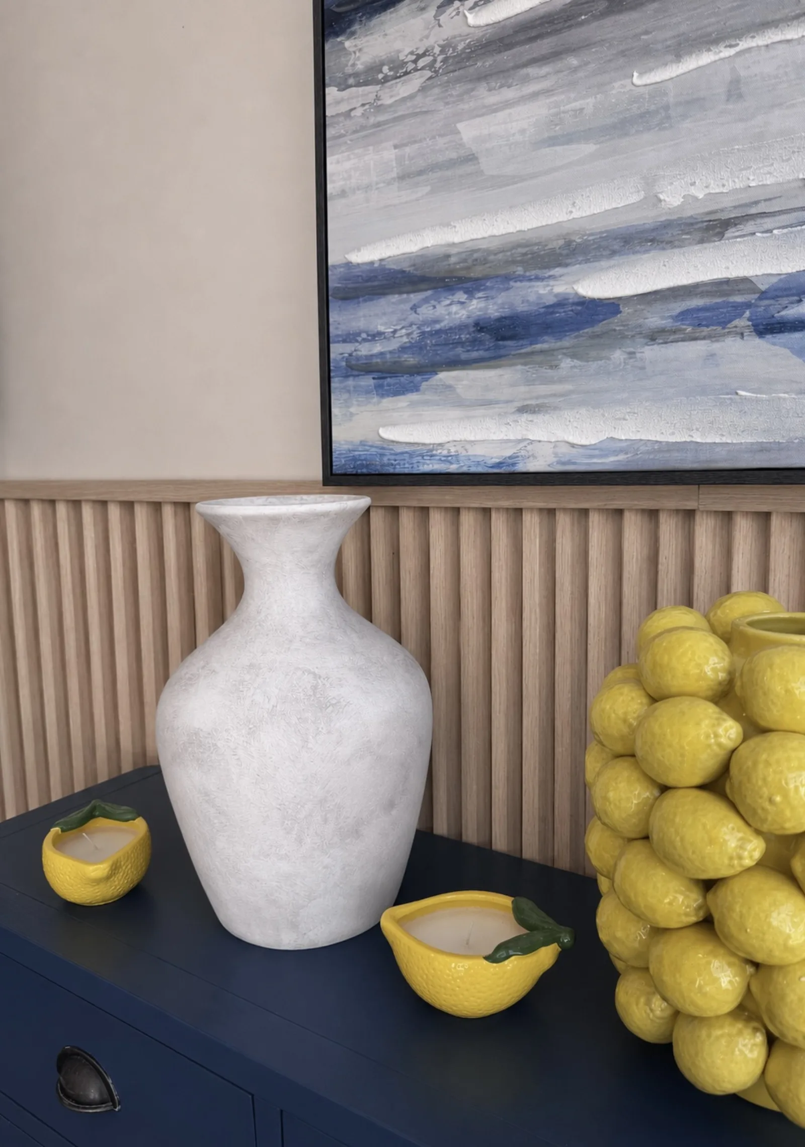 A white ceramic vase and lemons against fluted timber panelling