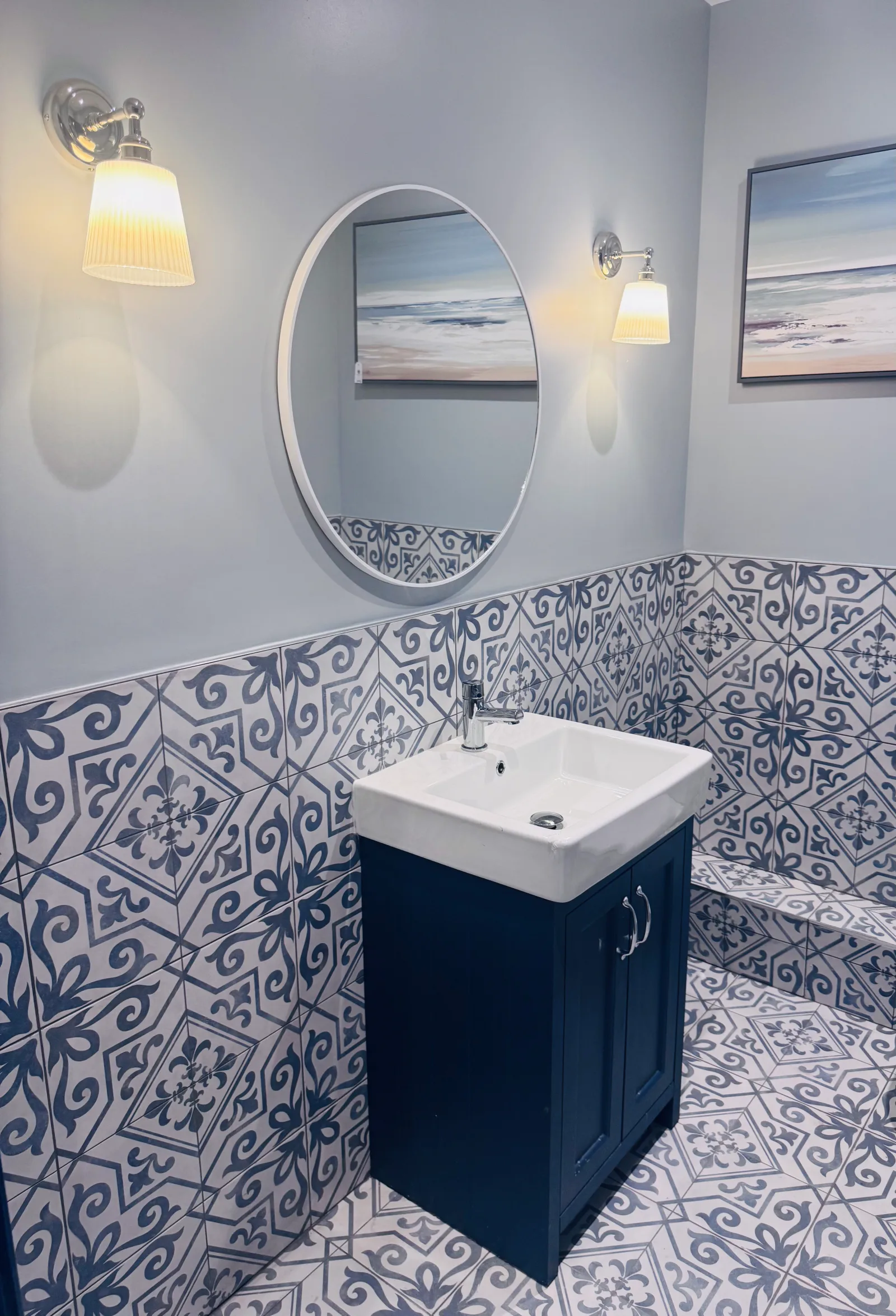 The cloakroom, with blue patterned wall tiles and a white basin