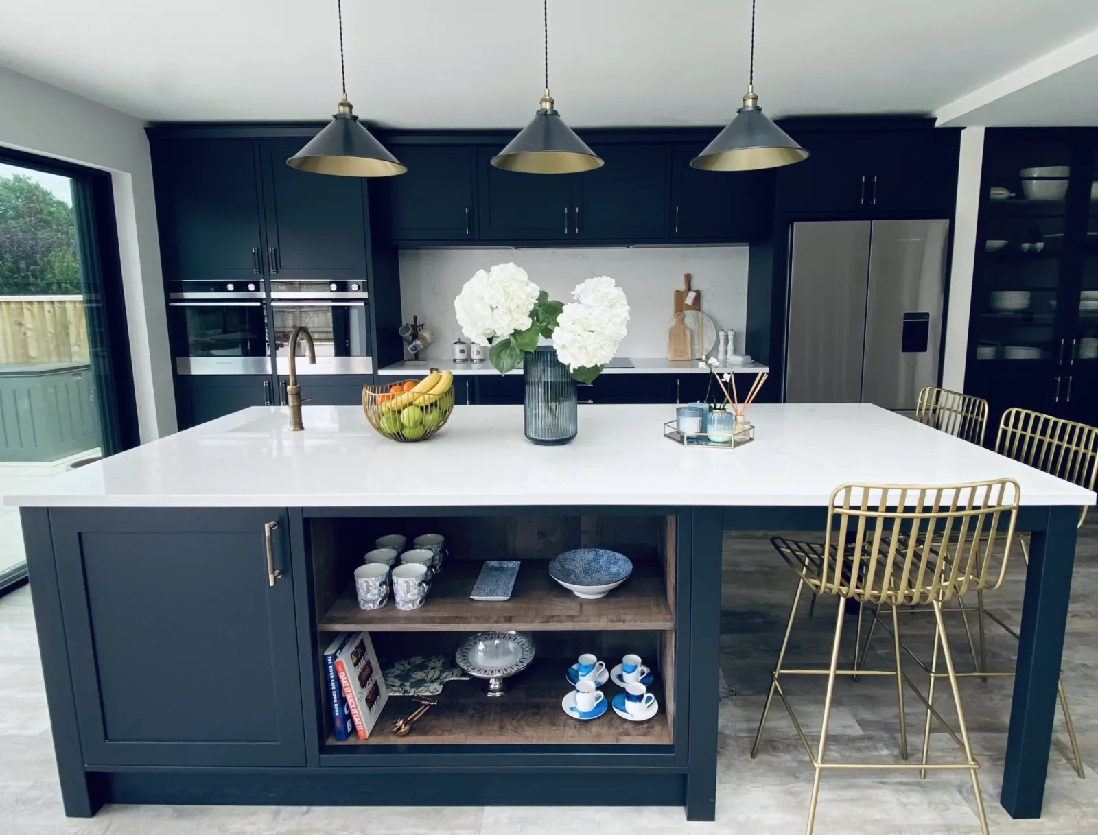 A navy kitchen island with a white worktop and open shelving