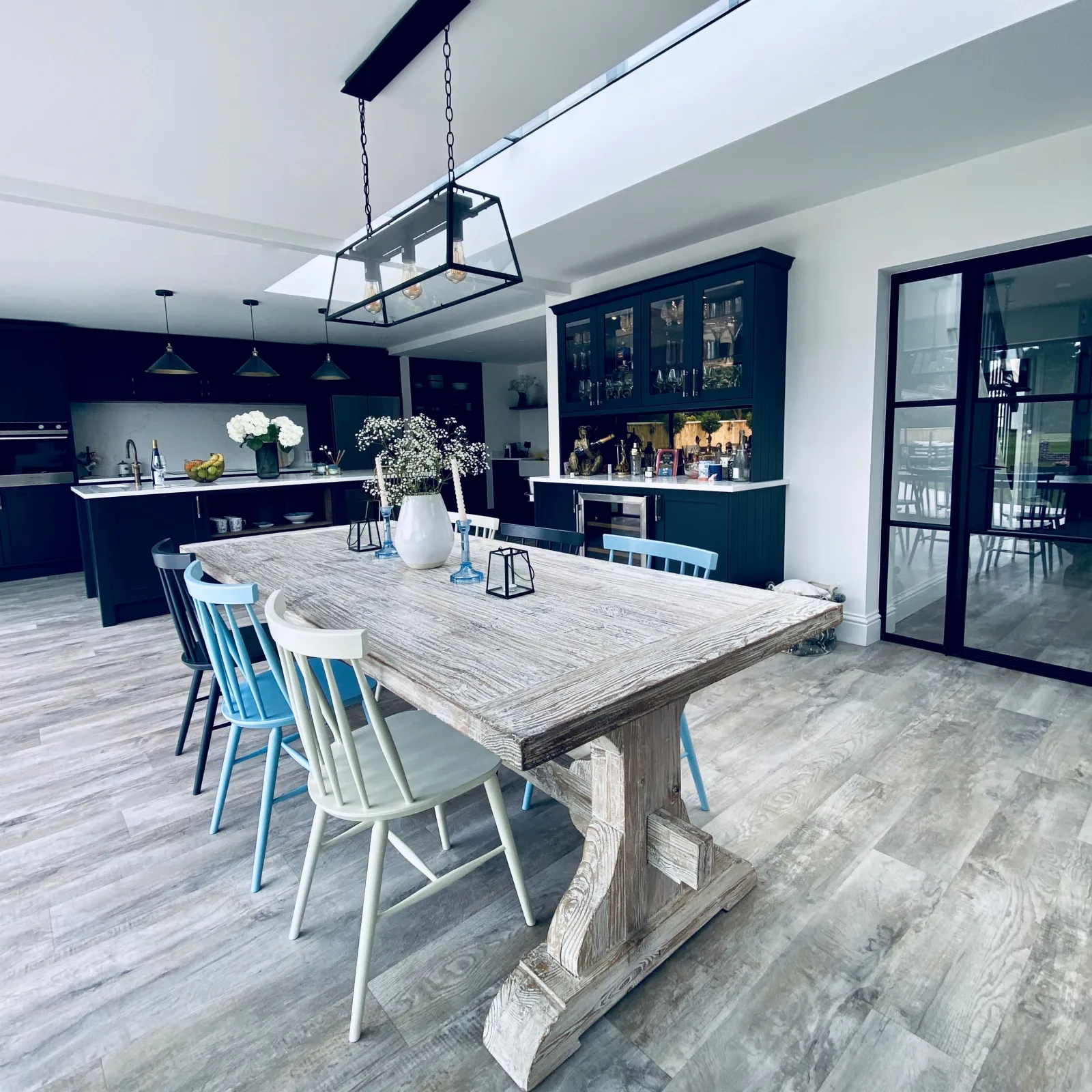 An open plan kitchen diner with a rustic table and blue dining chairs