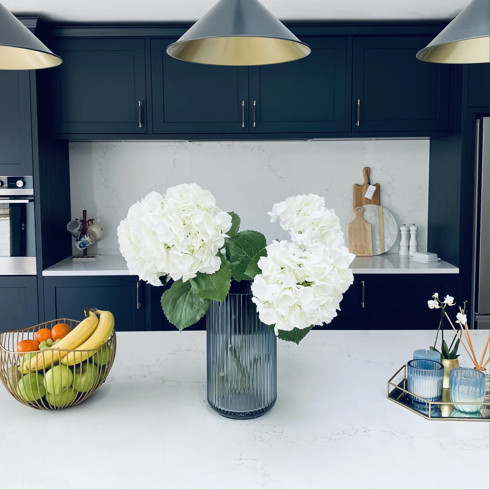White hydrangeas and a fruit bowl on a navy kitchen worktop