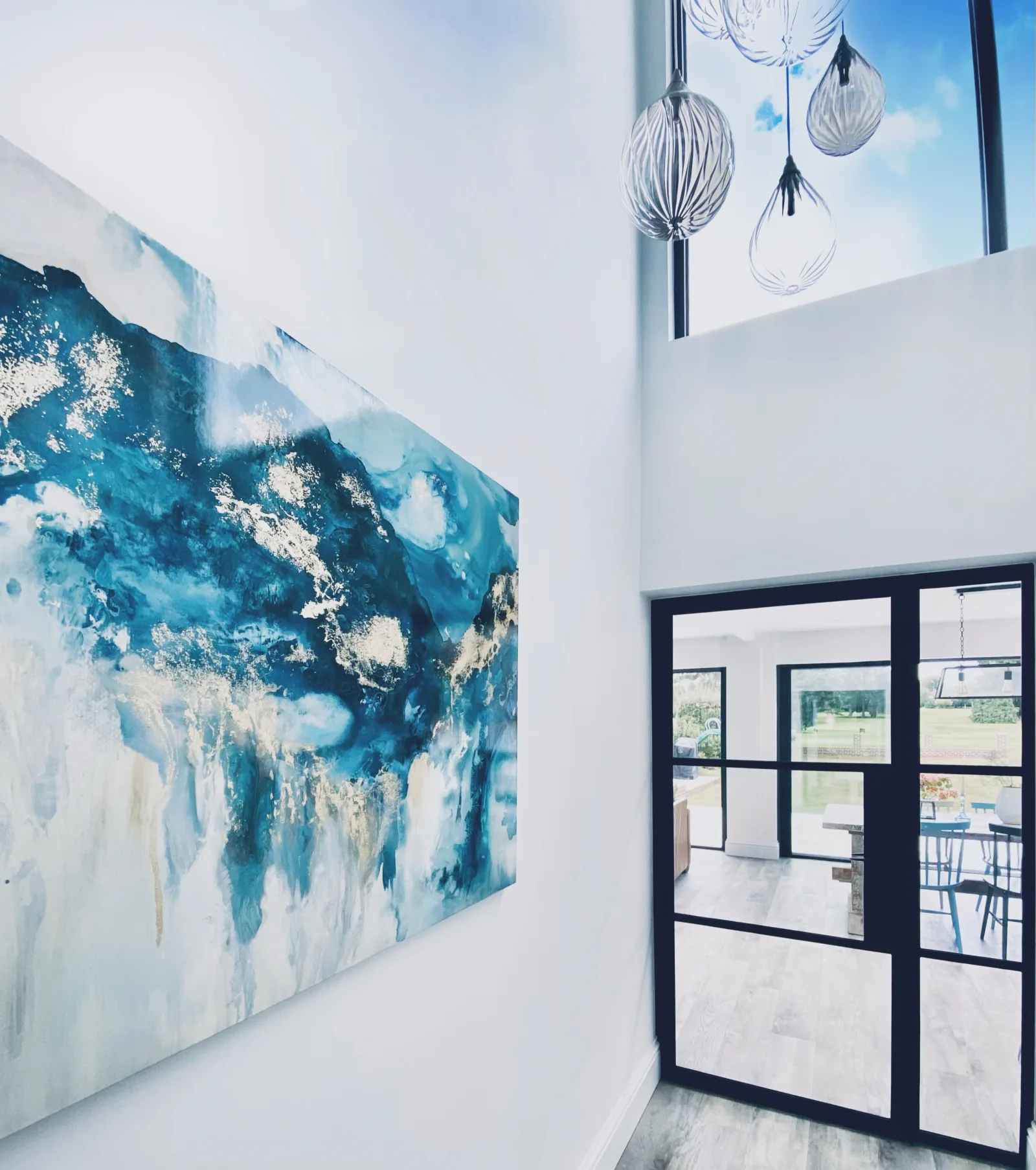 A large blue and gold abstract painting beside glazed doors