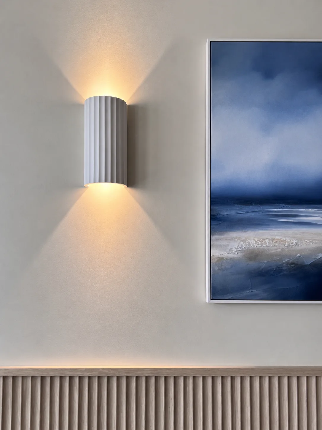 Fluted ceramic wall light throwing light up and down beside a seascape painting, Amalfi Bar & Cafe, Bideford, Devon