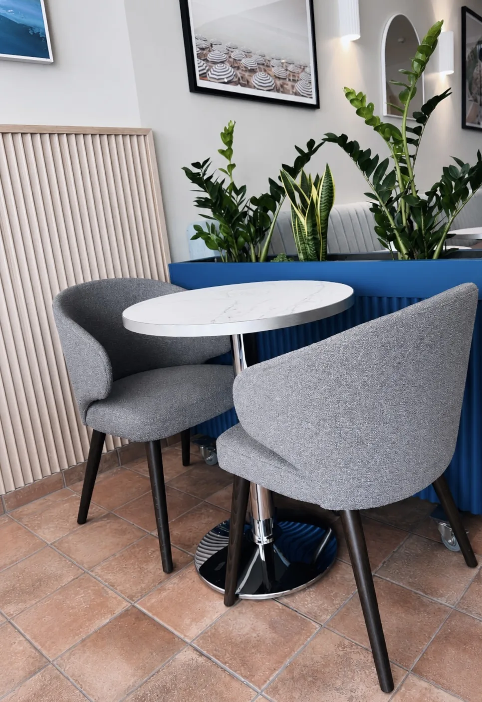 Marble topped table with two boucle tub chairs and planting behind, Amalfi Bar & Cafe, Bideford, Devon