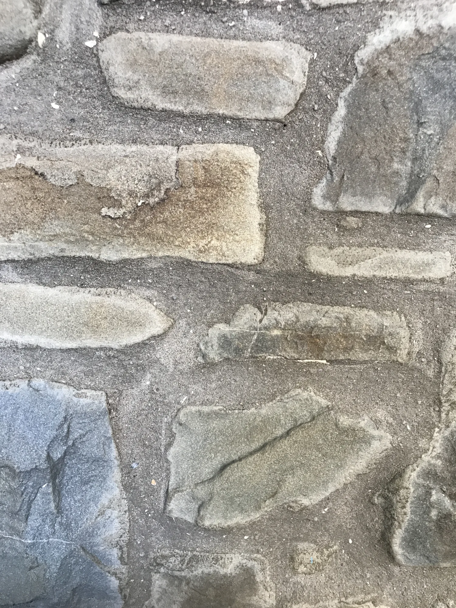 The cottage's original stone fireplace wall in grey, buff and blue-grey stone, at the thatched cottage in Appledore, Devon