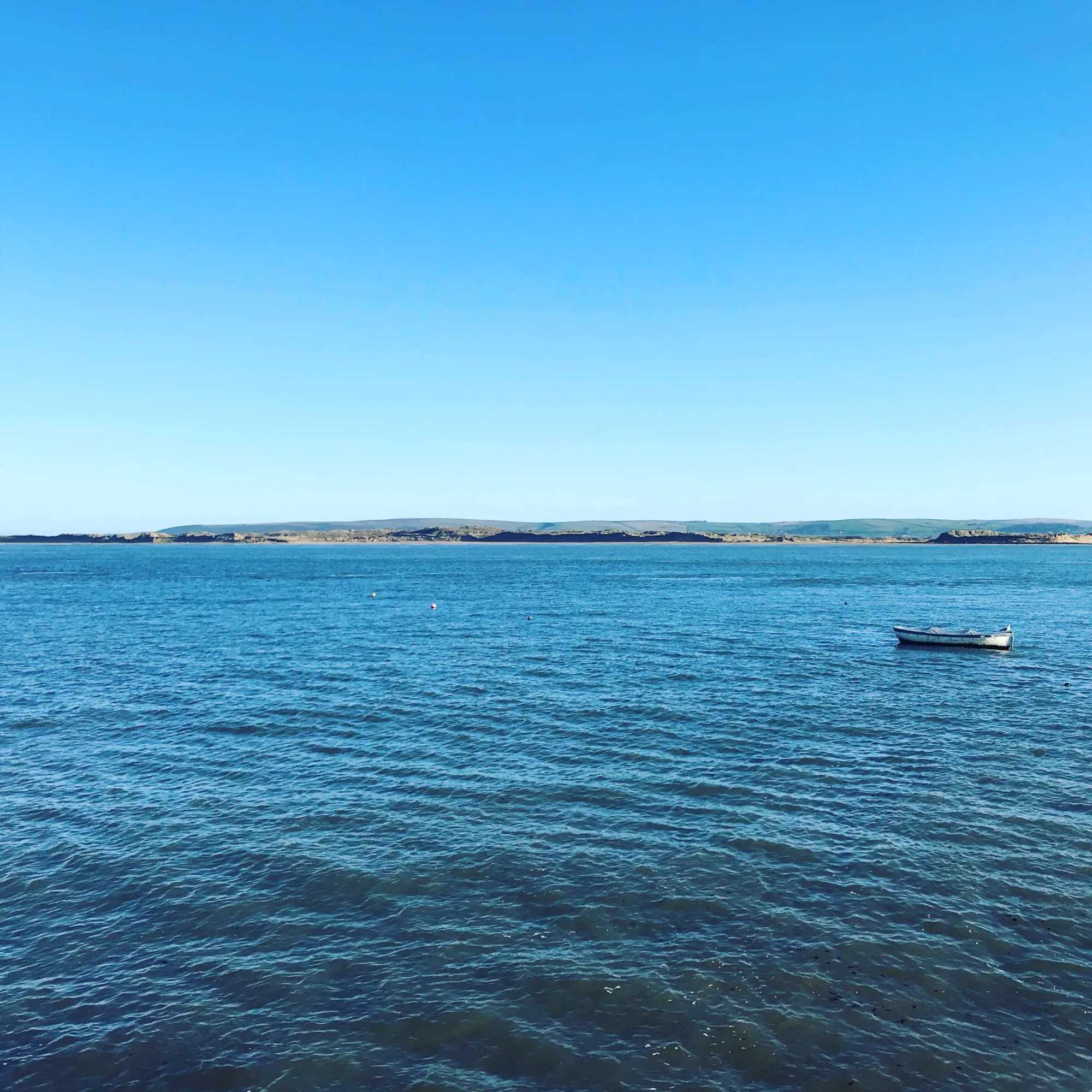 The estuary view from the cottage, a small boat moored on open water under a clear sky, Appledore, Devon