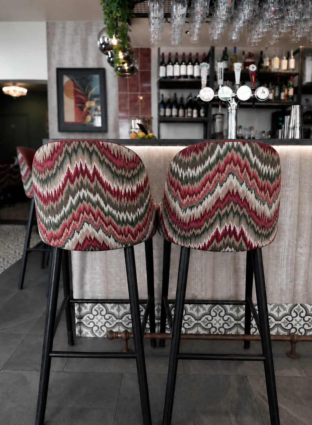 Flamestitch upholstered bar stools at the bar, with glassware and bottles behind, Belluno Restaurant, Bideford, Devon