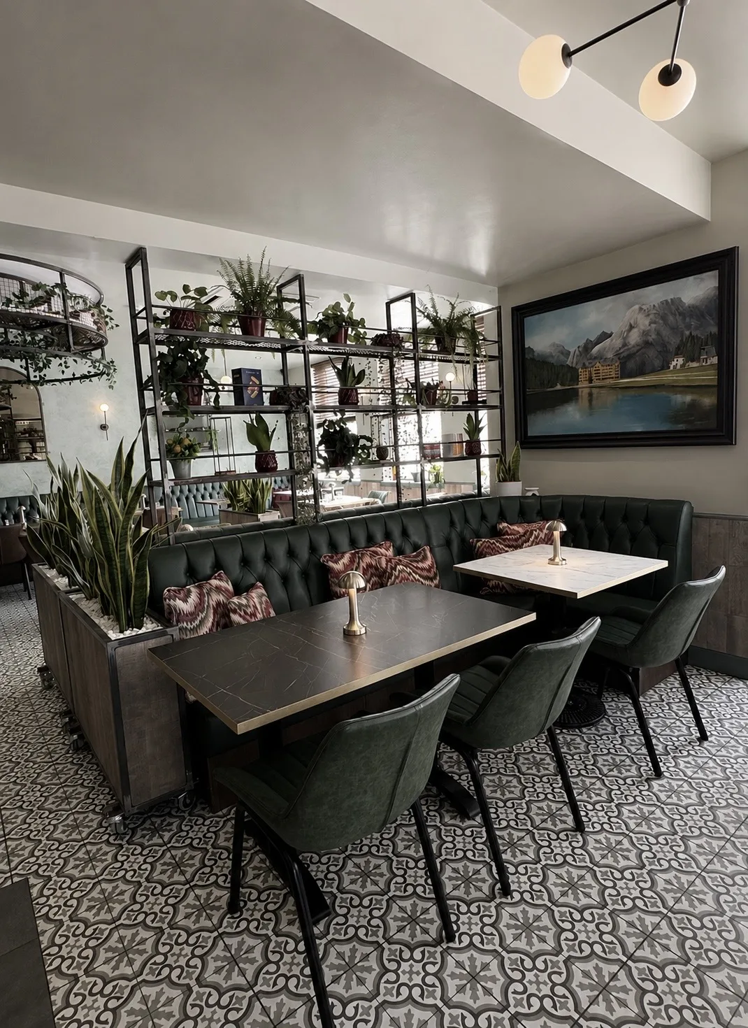 Dining tables and green leather chairs beside the planted shelving unit, Belluno Restaurant, Bideford, Devon