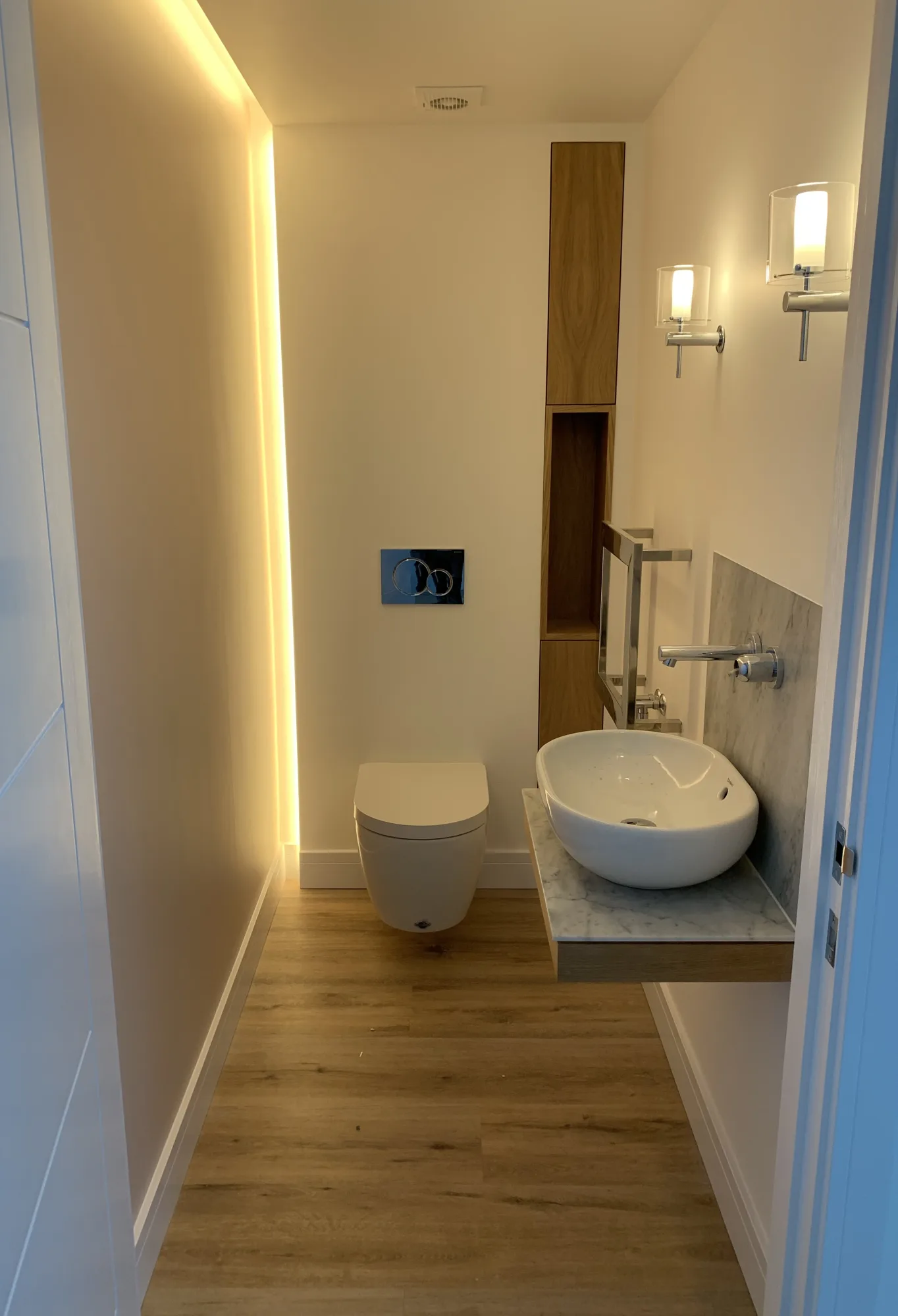 Downstairs cloakroom with concealed cove lighting, an oak niche and a marble topped vanity, Northam, Devon