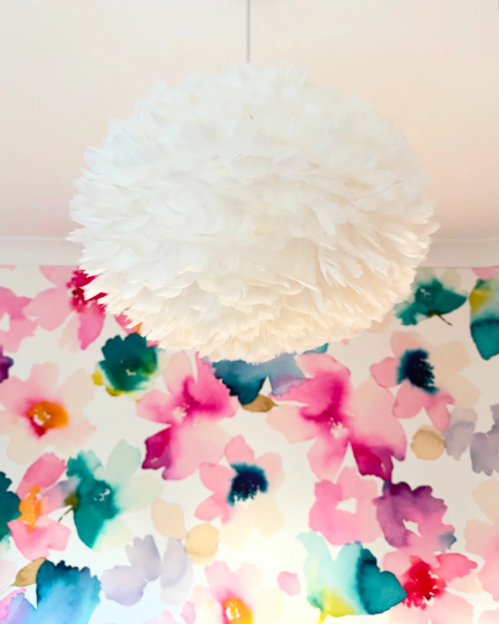 White Umage feather pendant hanging against watercolour floral wallpaper, Stevenstone, Devon