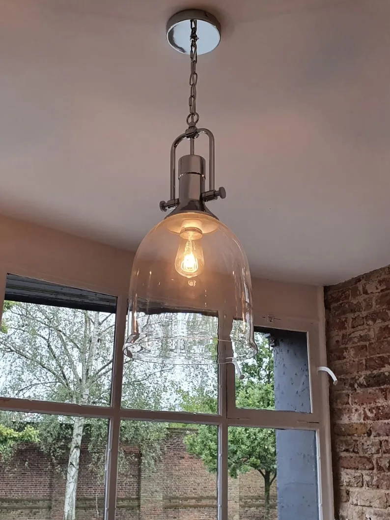 Glass dome pendant light on an antiqued brass fitting, hung against the garden windows, Ethos HQ, London