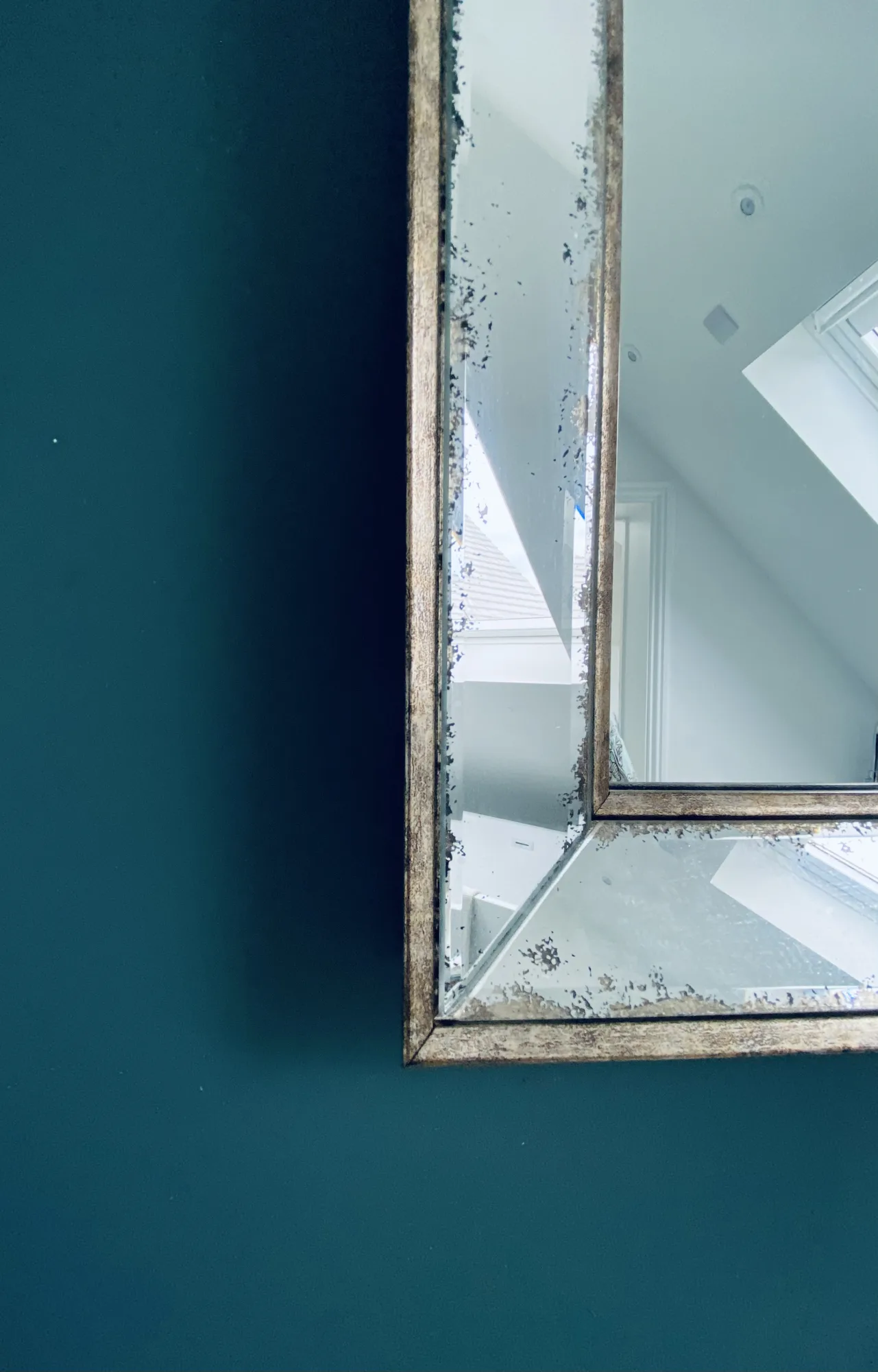 Corner of an antiqued glass mirror against a deep teal ensuite wall, Topsham, Devon